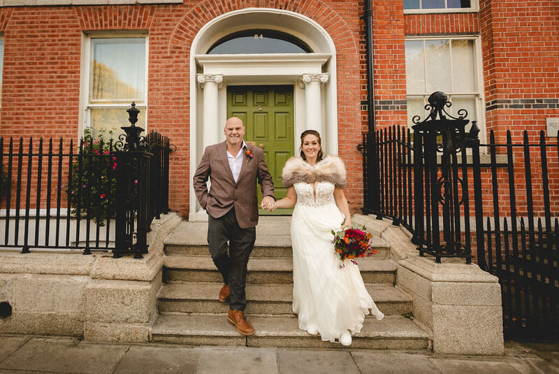 Bride and groom walking down stairs in front of a brick building in Ireland