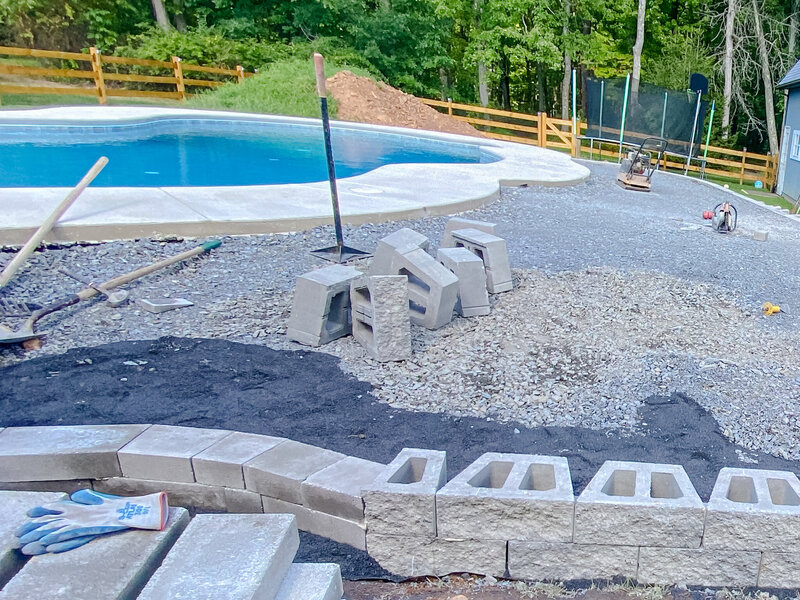 In process shot of the pool deck being built with the pool in the background and tools scattered around