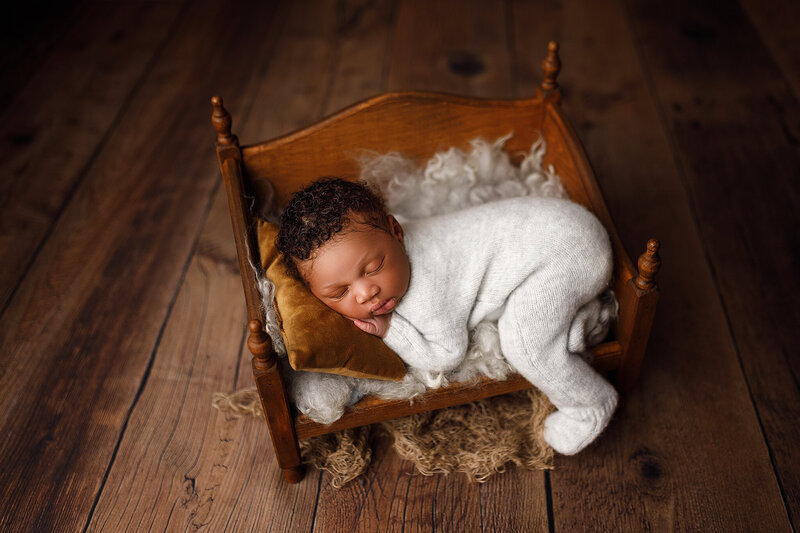 Newborn baby boy in bed prop