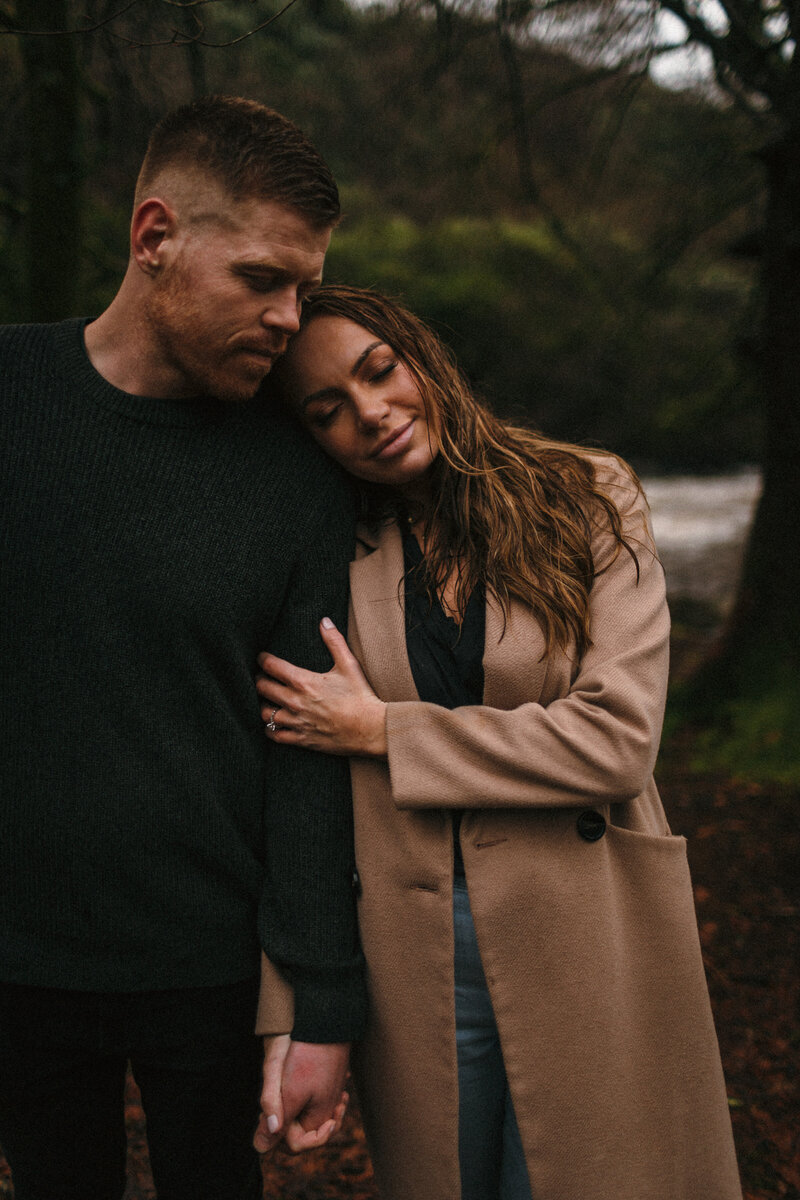 Attractive couple rest together during a rainy engagement shoot on Dartmoor 