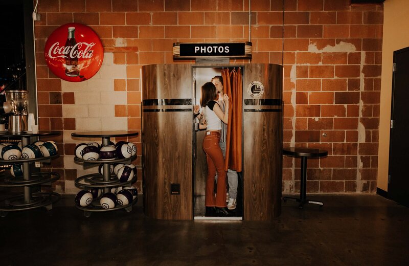 Couple in Photo Booth With Brick Wall Background