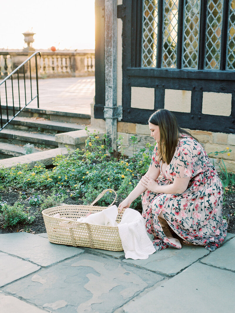 A mother reaching down to a baby in a basket at a newborn photography session in Richmond by Katie Stansfield Photography.