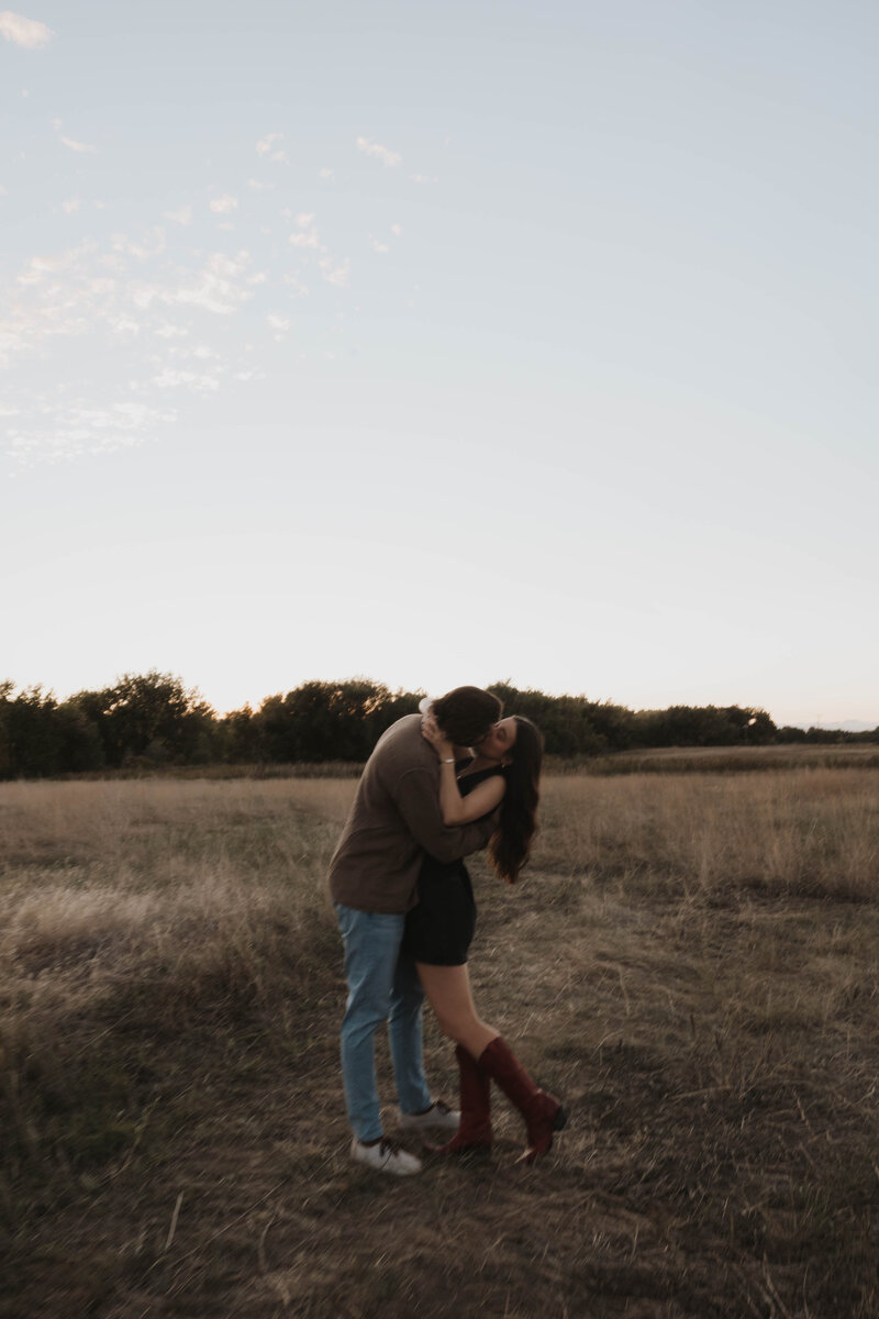 romantic and documentary engagement photos  of a couple kissing in a field