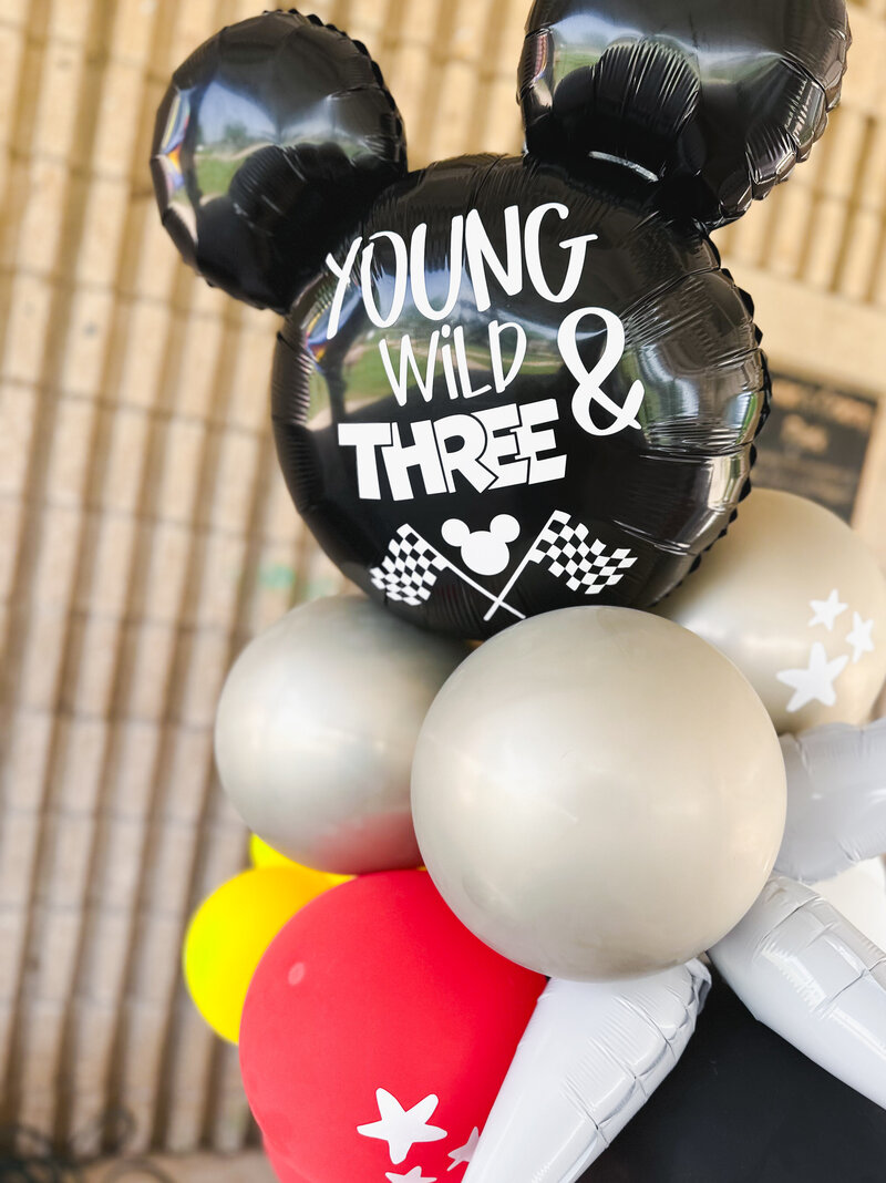 Balloon tower with black, gold, red and yellow balloons for a birthday party.