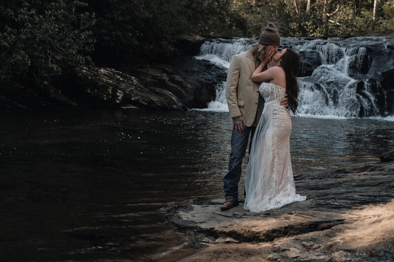 Couple shares a kiss at a waterfall