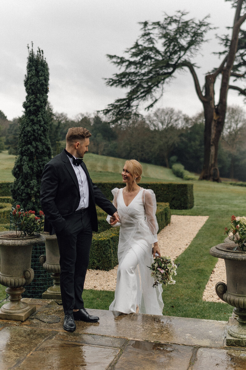 A wedding photographer captures the moment a bride and groom embrace on a summers day outside the elegant wedding gardens.