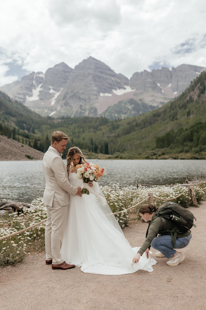 Montana Wedding Photographer helps a bride fluff her dress for portraits in front of Maroon Bells in Colorado.
