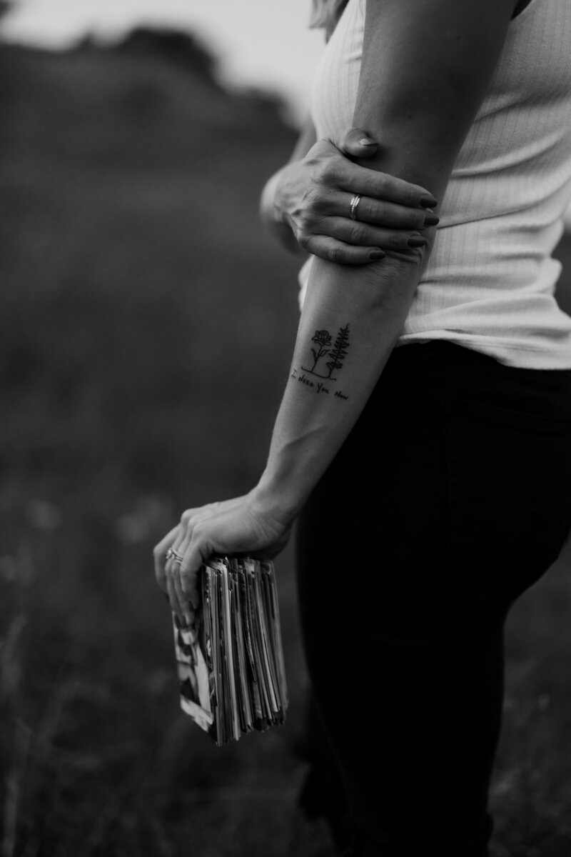 woman holding photos tattoo on her arm