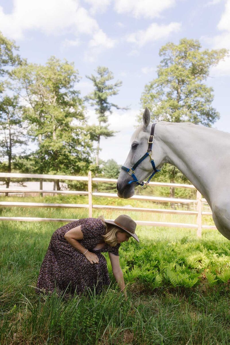 Woman with a white horse in a grassy field during a one-on-one equine healing session