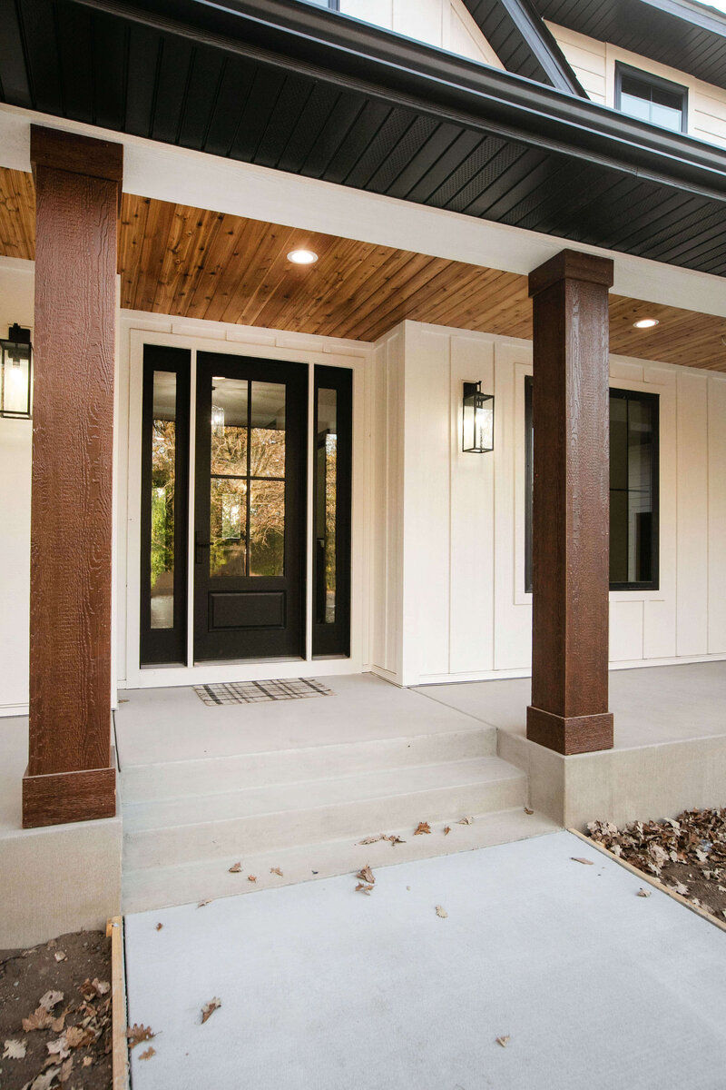 Open concept custom front porch on Otsego, Minnesota home with white siding, wood pillars and accents designed by Cornerstone Custom Builds