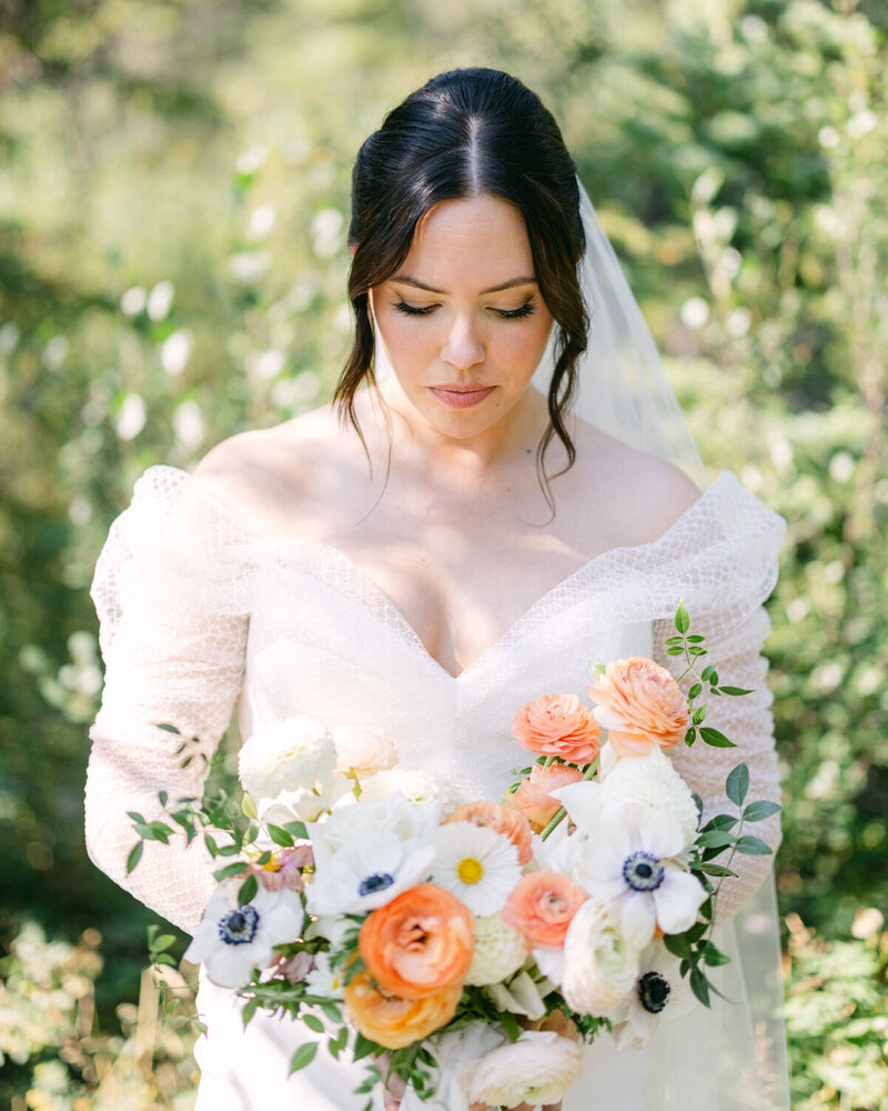 This beautiful photograph captures a bride holding her floral bouquet from Flores and Pines in Calgary, adding elegance and charm to her wedding day.