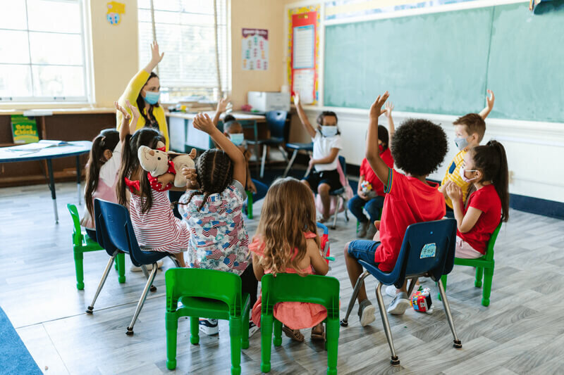 children raising thier hands in classroom