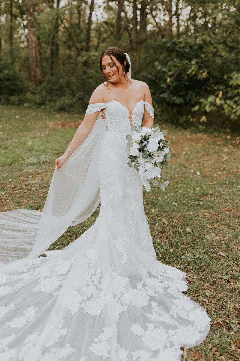 Pretty bride holding her floral bouquet and veil