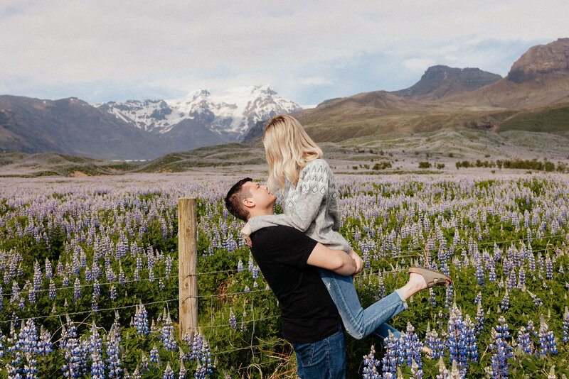 adventurous engagement photos in a flower field with snow covered mountains in the background