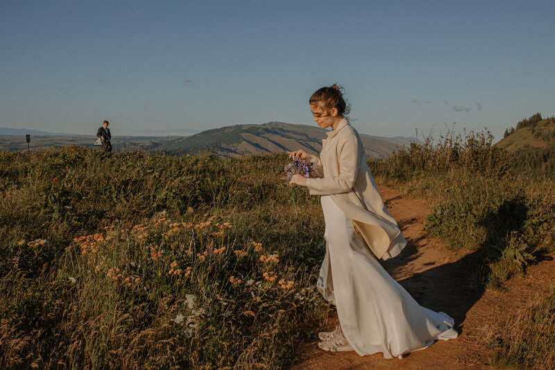 Bride picking wildflowers on mountain top