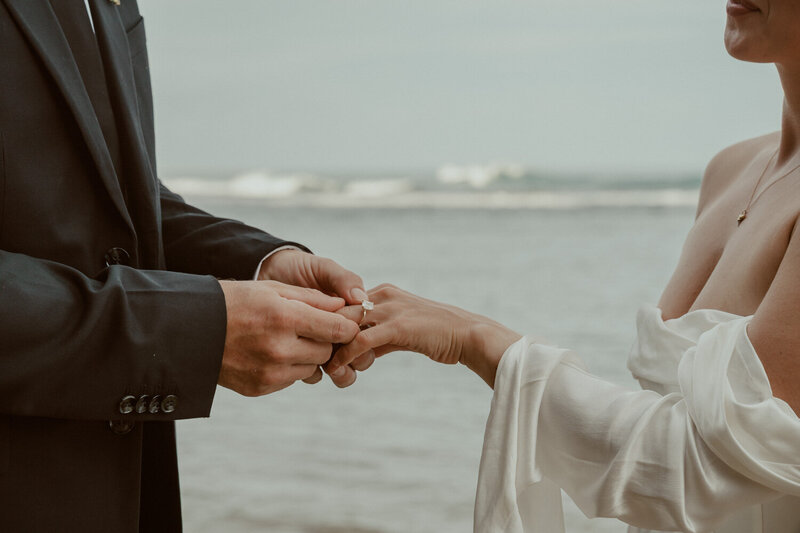 bride and groom exchanging wedding rings at the beach during their hawaiian elopement ceremony