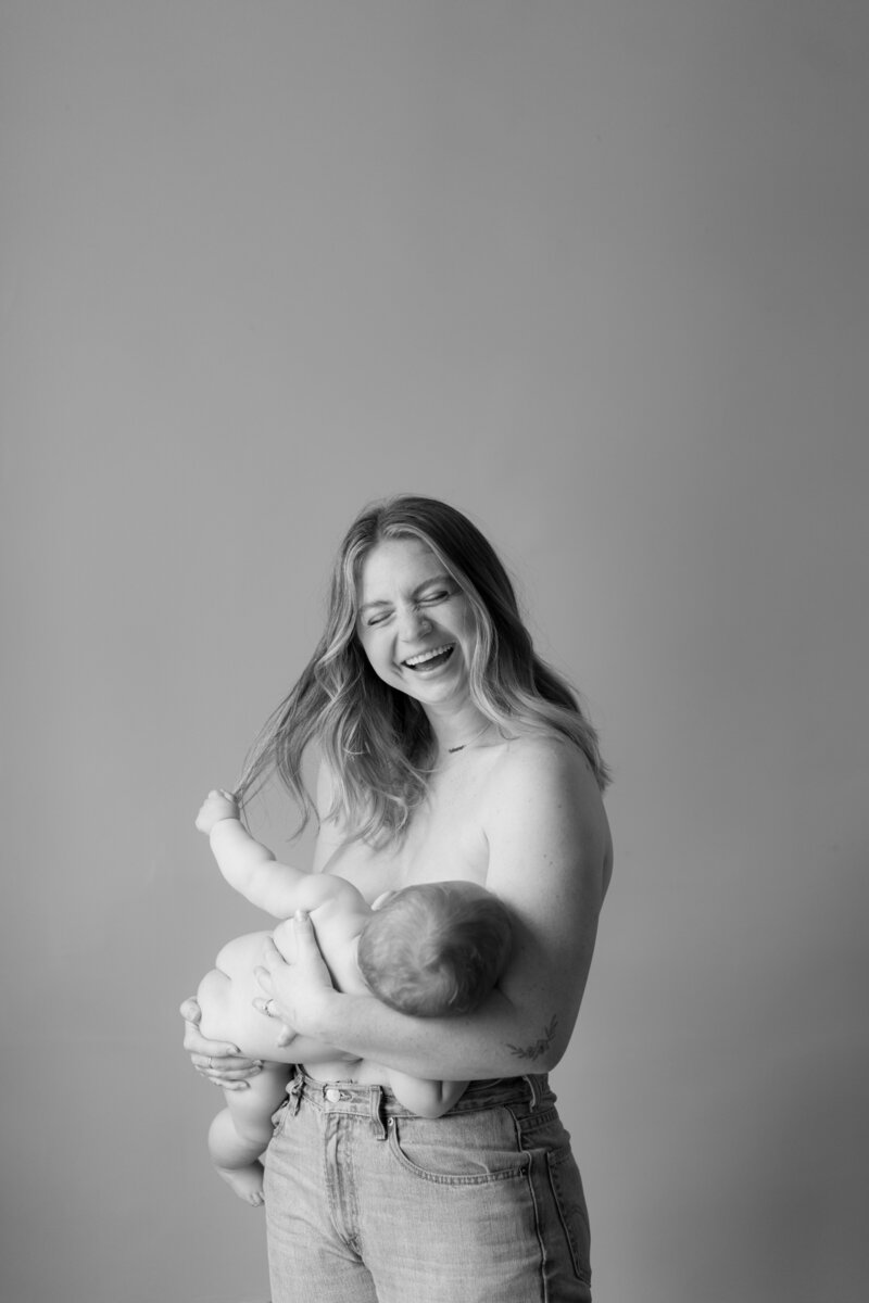 Portrait of a happy, laughing mother nursing her baby