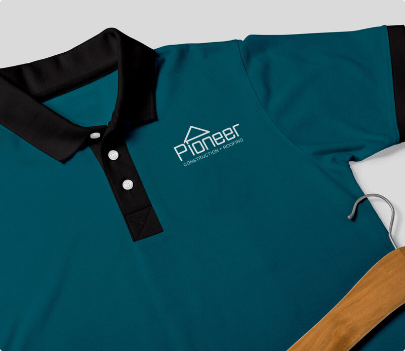Teal polo shirt laying down with Pioneer Construction logo on front.