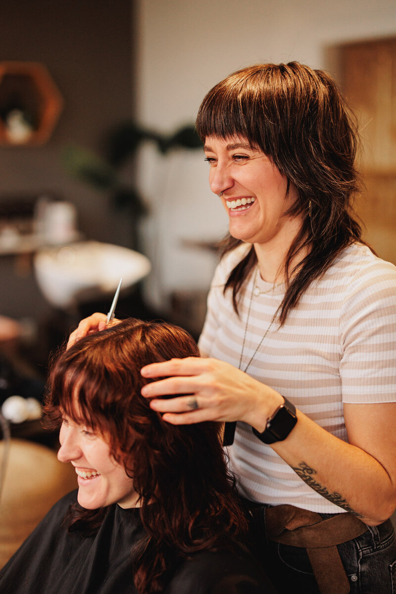 Chelsea smiles while working on a clients hair at The Collective Beauty & Wellness hair salon in Eugene.