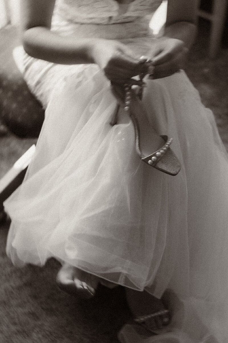Bride putting on strappy heels with pearl accents