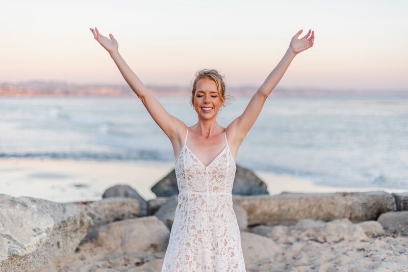 Woman smiling on beach raising bot hands up to the sky