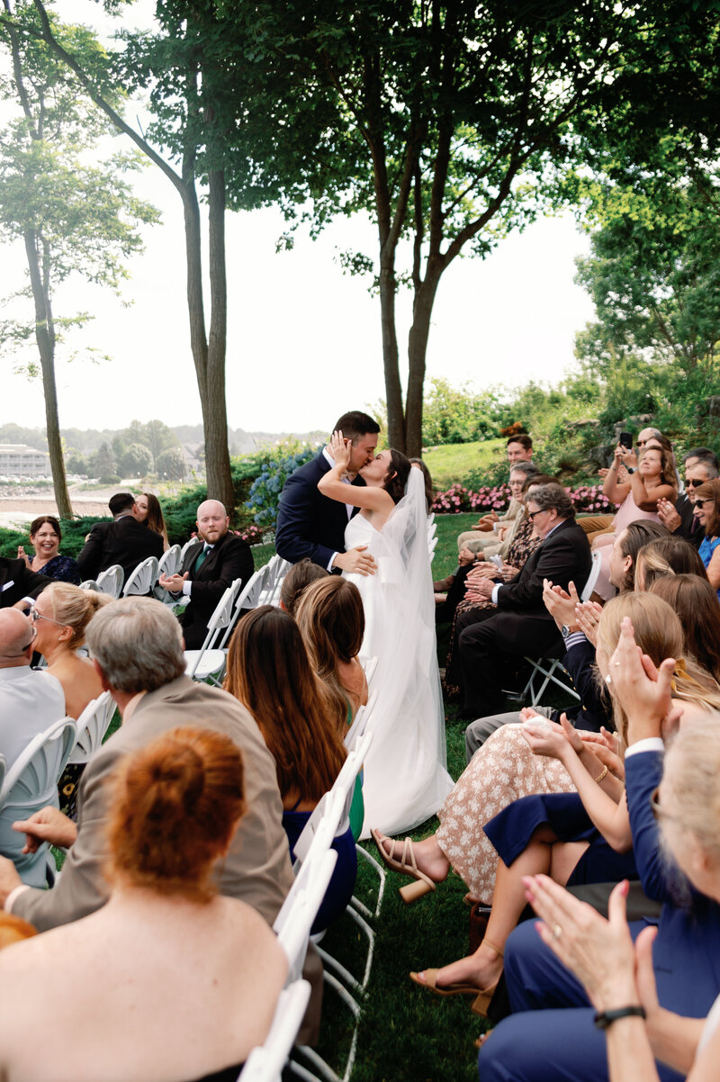 Wedding photo of couple kissing in the aisle after their wedding ceremony just married