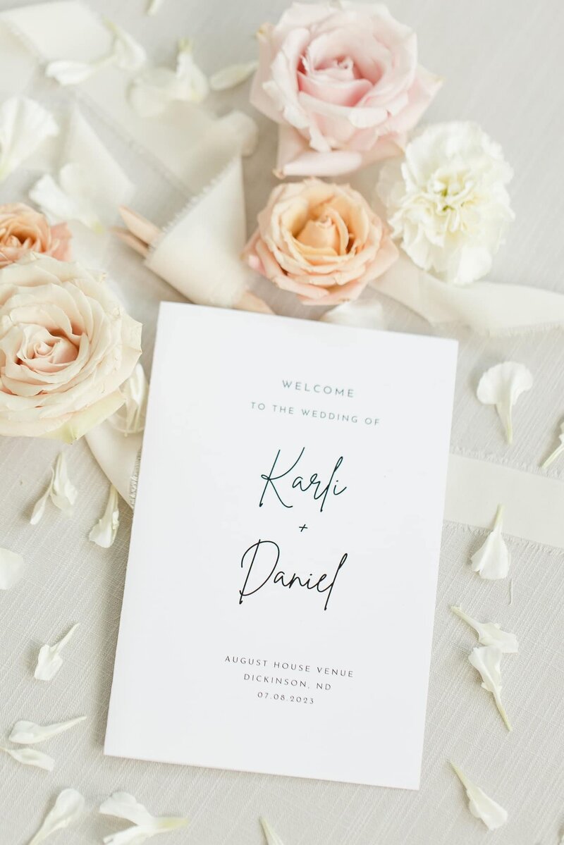 Flat lay of wedding invitation suite with floral accents, styled on a marble tabletop at August House venue.