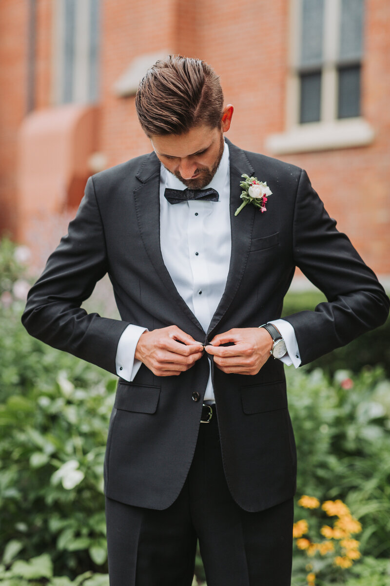 Groom buttoning up his suit jacket on his wedding day