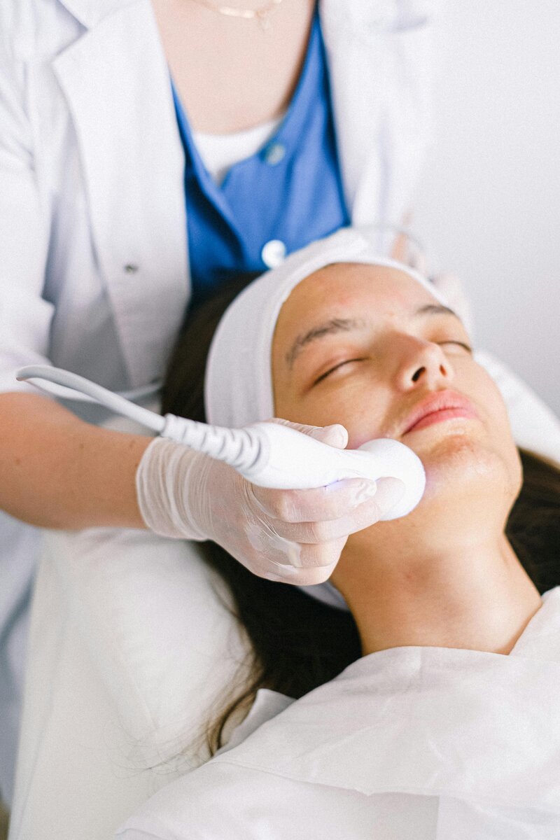 Nurse treating woman's face with laser treatment