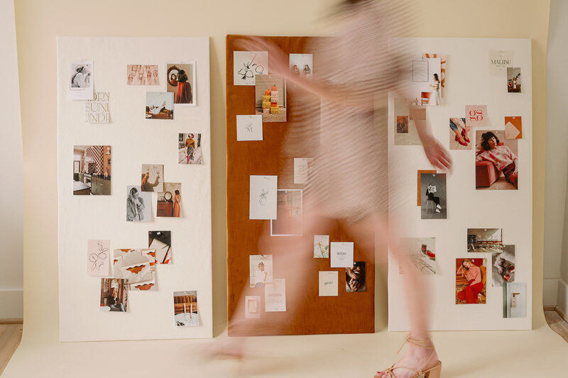 blurred photo of a woman walking in front of colored inspiration boards
