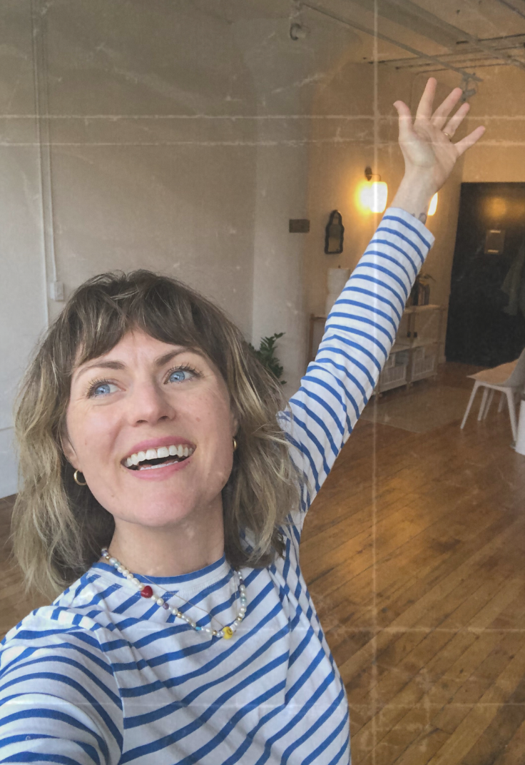 Psychiatrist and founder of Held Space, Laura Temple, smiles gleefully with her hand raised in the air. Photo has a folded, film-like overlay.
