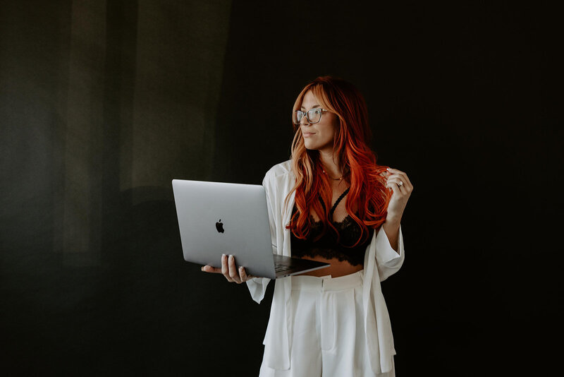 woman in a white blazer set holding a laptop