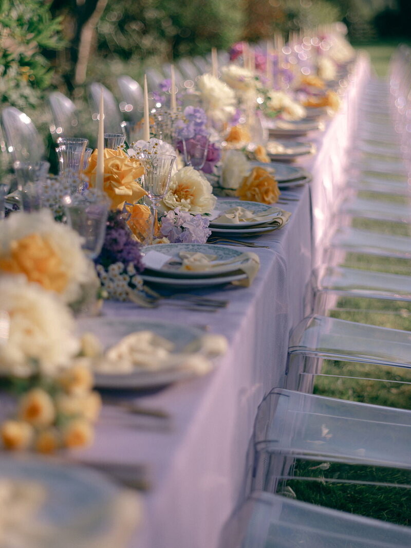 An outdoor wedding table styled with yellow and lilac florals