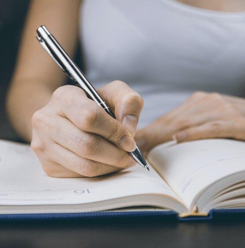 hand holding pen writing in notebook