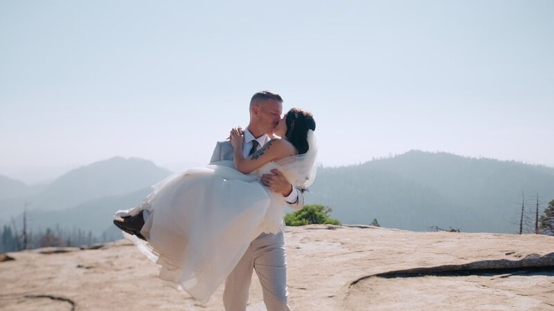 Newlyweds embracing on Beetle Rock in Sequoia National Park, surrounded by mountains.