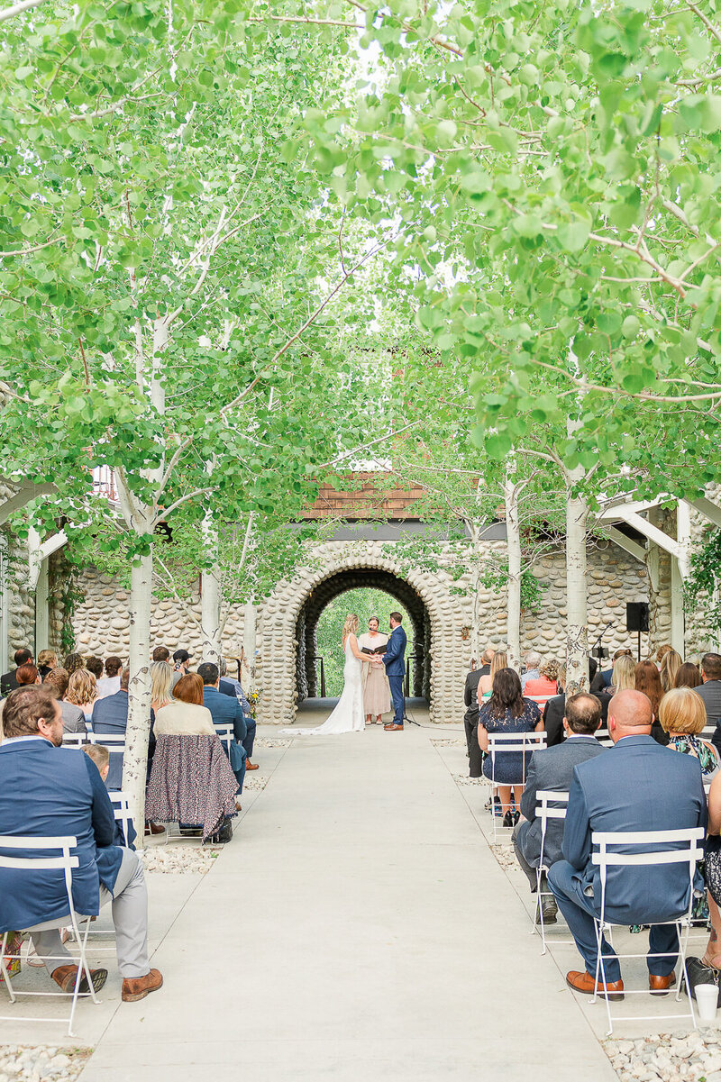 Outdoor wedding ceremony in a European courtyard filled with aspen trees.