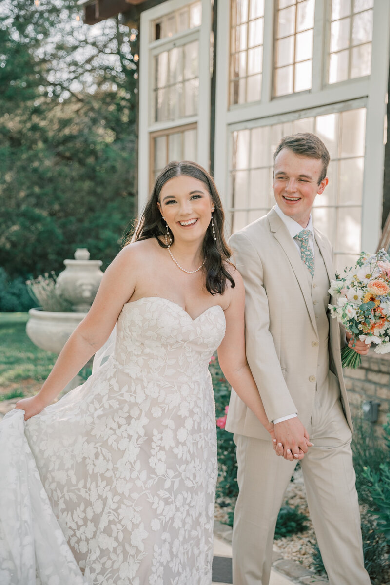 Three Oaks Manor Wedding | Newlyweds walk hand in hand by the greenhouse
