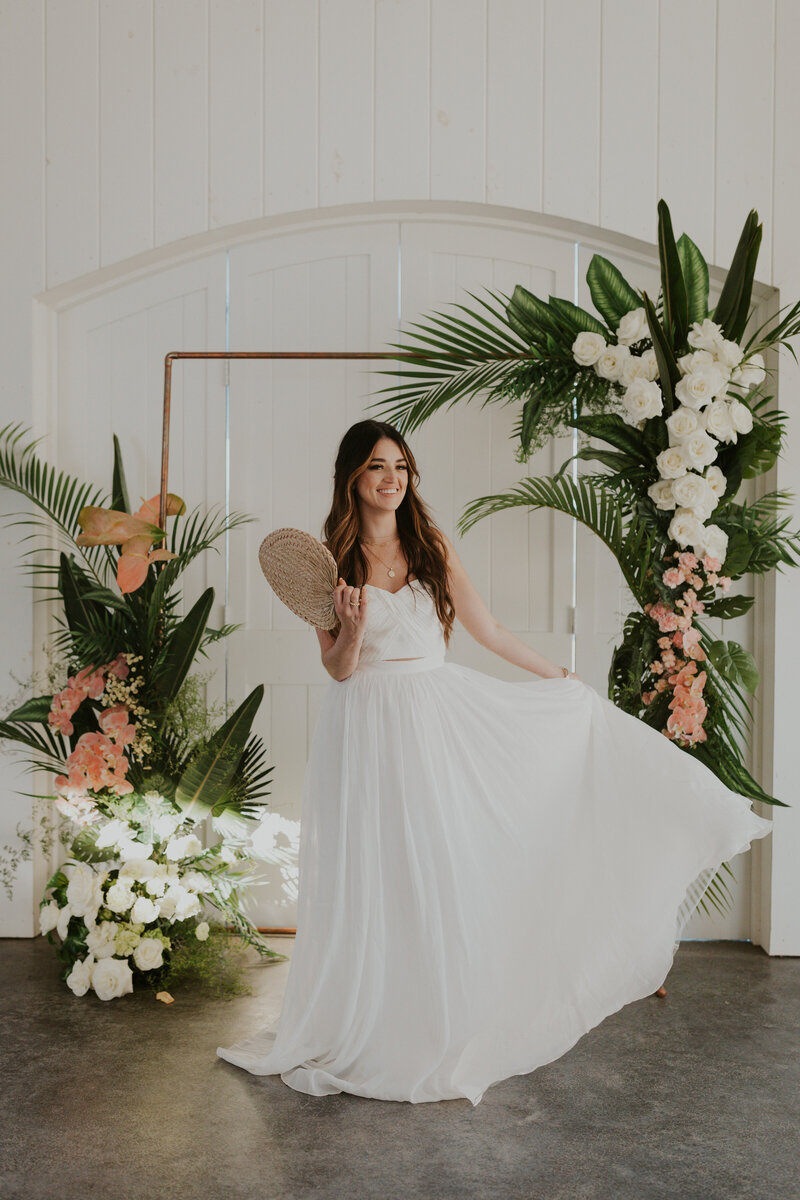 Bride shows off her stunning Vera Wang wedding dress in front of tropical summer floral archway