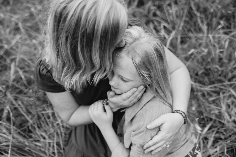 Black and white portrait of a mother kissing her daughter during a family portrait session in Bonne Terre, Missouri. 