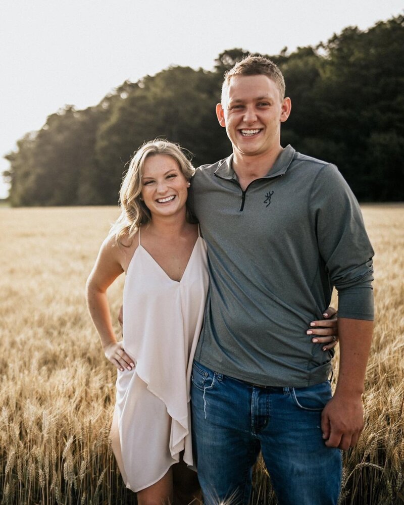Chelsea and Jeff posing at golden hour amongst a wheat field.