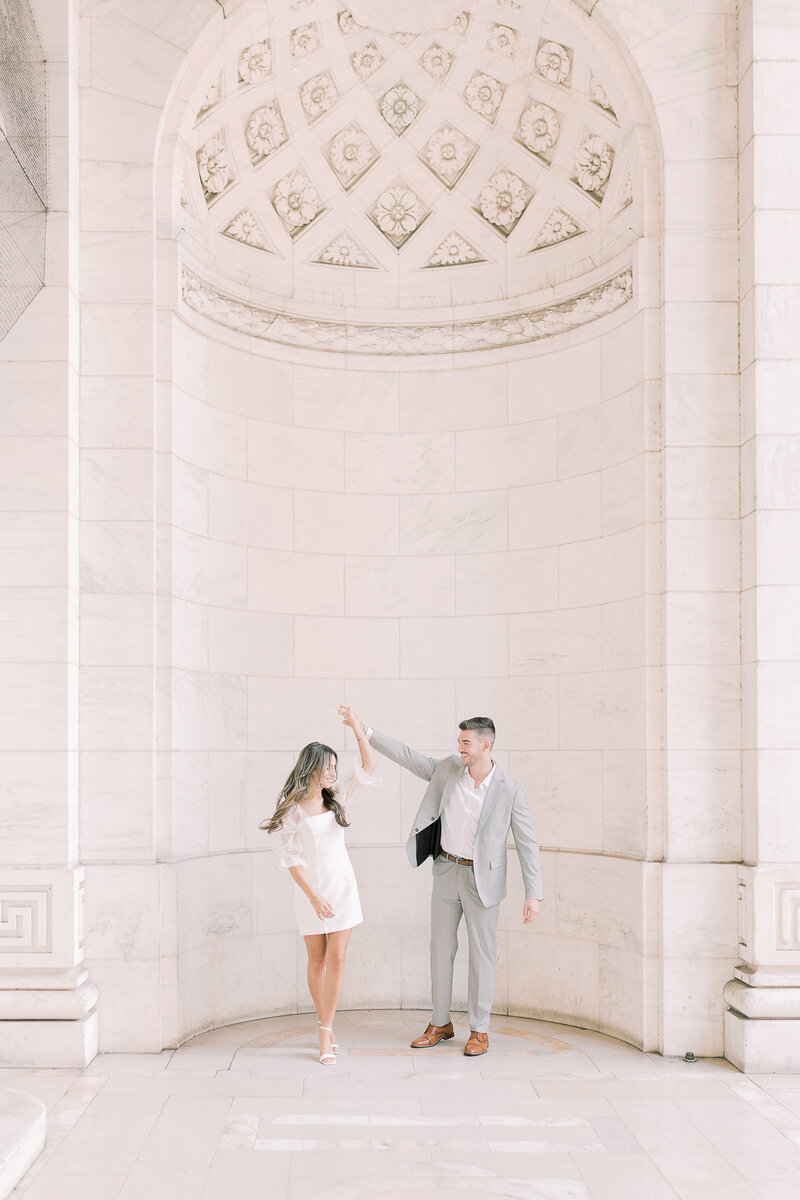 Couple dancing together in front of a wall with high ceilings