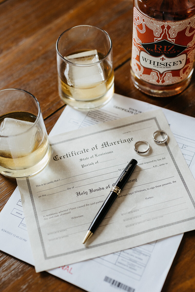 Marriage license next to two glasses of whiskey.