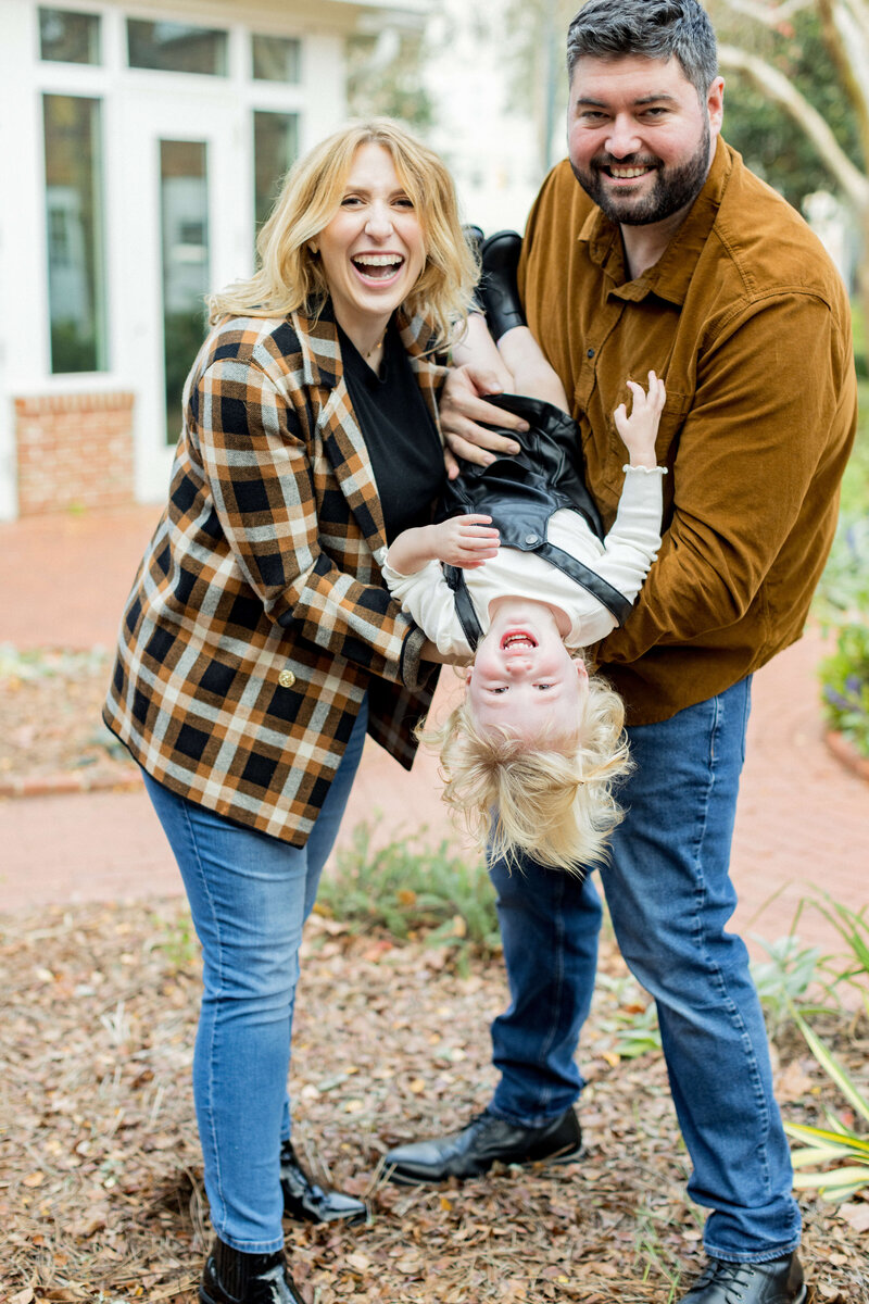 Another joyful and candid family moment! This portrait captures pure happiness, with both parents beaming as their little one giggles upside down in dad’s arms. The playful energy, natural laughter, and warm tones make this a perfect representation of the love and connection shared in this growing family.