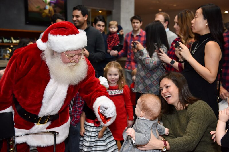 Santa greeting party guests at holiday party