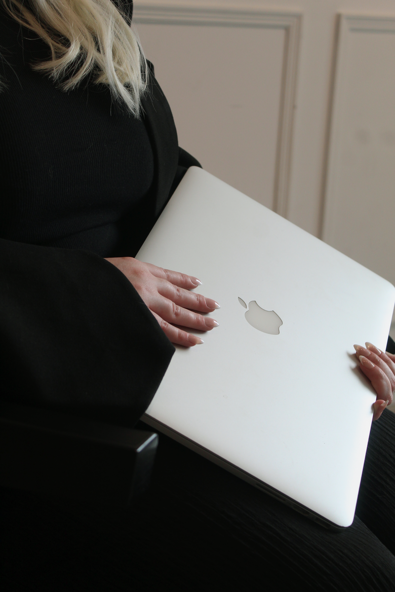 A zoomed up coloured image of a woman in a suit, holding onto a laptop.