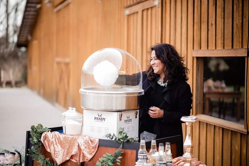 Small business owner making cotton candy outside a wedding venue for guests
