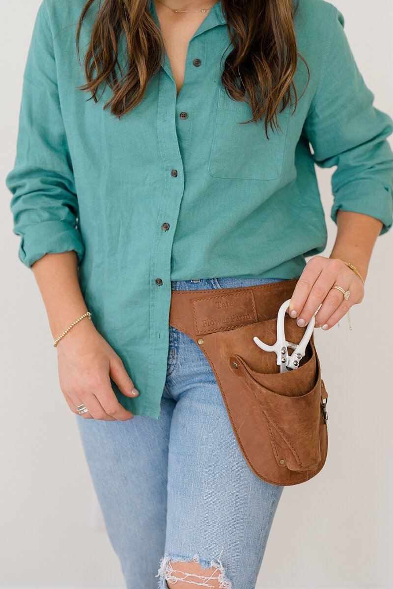 Columbus photographer photographs florist putting sheers in the pocket of her leather gardening belt