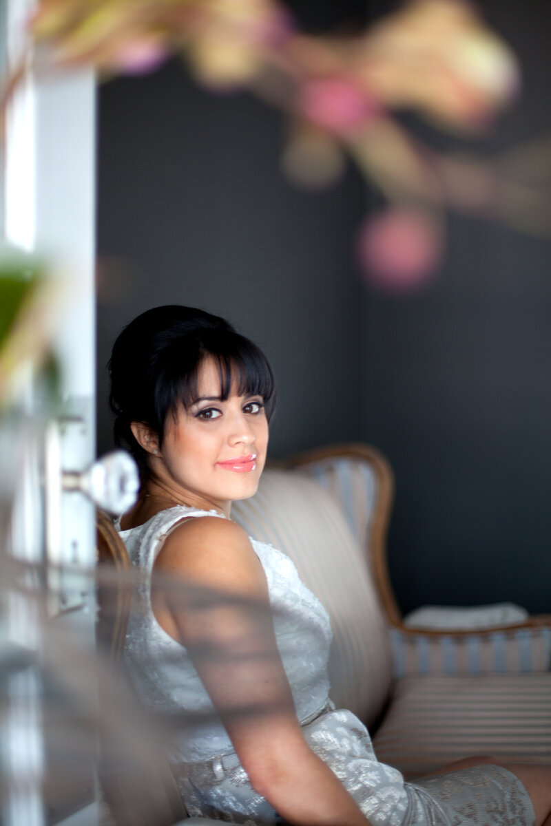 women with short bangs sitting on sofa smiling at camera