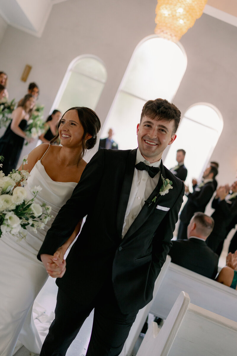 Married Couples Walks Down Aisle in Maine Chapel with Flowers in Hand