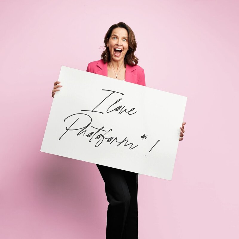 Woman against a pink background holding an 'I love Photoform*' sign.